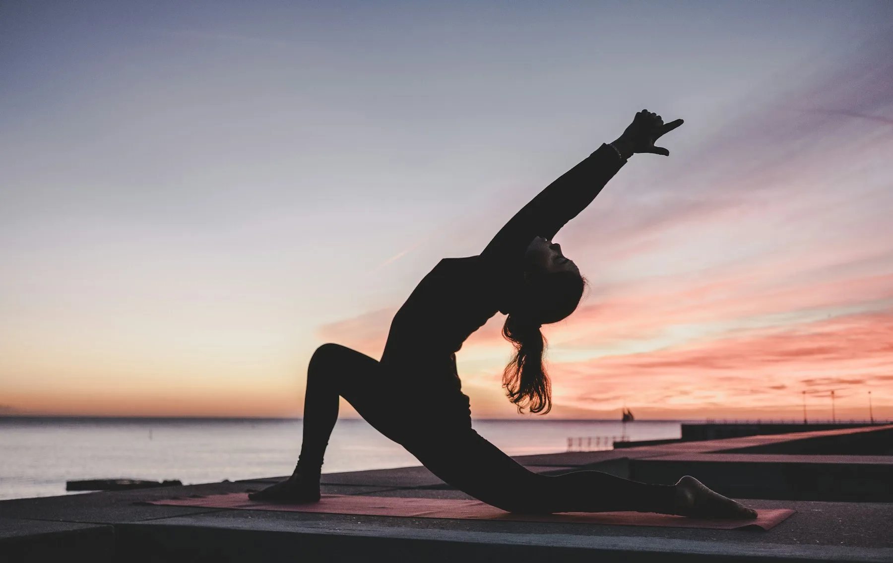Silhouette of a yogi in a backbend pose against a dramatic sunset sky
